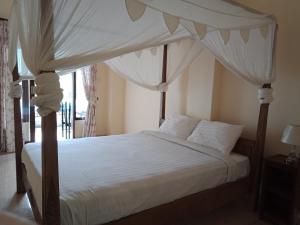 姆杜克阿迪拉沃恩民宿的卧室配有带白色床单和枕头的天蓬床。