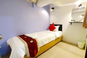 曼谷Khaosan Art Hotel - SHA Plus Certified的一间小卧室,配有一张带红色枕头的床