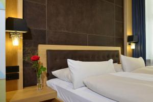 慕尼黑图芭拉乌酒店的一间卧室设有两张床和一个玫瑰花花瓶。