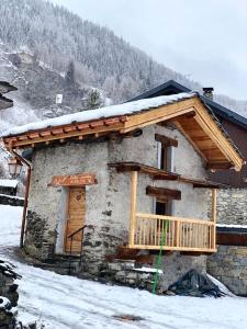 蒂涅le mazot d'urbain的雪中带木制阳台的小房子