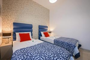 普拉San Martino Rooms的一间卧室配有两张带蓝色和红色枕头的床