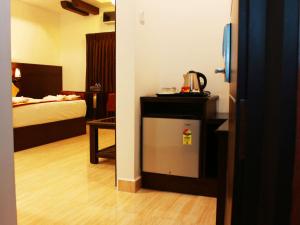 钦奈Staylite Suites的酒店客房配有一张床和一台小冰箱