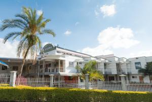 富萨加苏加卡塔蒙酒店的一座白色的建筑,前面有棕榈树