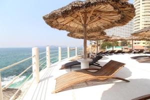阿卡普尔科Suites Torres Gemelas VIP的一个带椅子和遮阳伞的阳台,并享有海景。