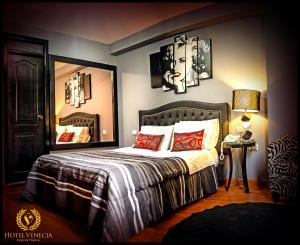 瓦努科Hotel Venecia的一间卧室配有一张带红色枕头和镜子的床