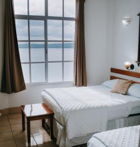 弗洛勒斯阿米莉亚卡萨酒店的一间卧室设有两张床和大窗户