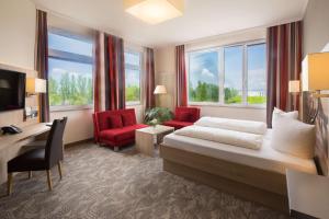 莱茵河畔威尔Best Western Hotel Dreiländerbrücke Weil am Rhein / Basel的酒店客房,配有一张床和两张红色椅子
