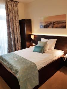 KókaHotel Czinege & Étterem的一间卧室配有一张带白色床单和蓝色枕头的大床。