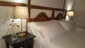 圣马丁德巴尔代格莱西亚斯Hotel Labranza的一张带白色床单的床和床头柜上的花瓶