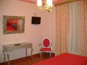 洛斯帕拉西奥西维利亚夫兰卡圣克鲁斯酒店的客房设有桌子、红色椅子和书桌。