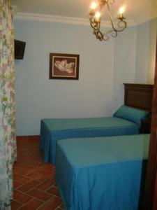 洛斯帕拉西奥西维利亚夫兰卡圣克鲁斯酒店的一间设有两张蓝色床的客房,墙上挂着一张照片
