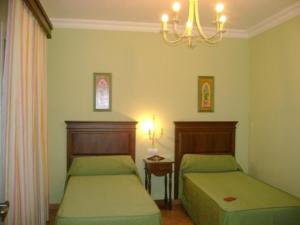 洛斯帕拉西奥西维利亚夫兰卡圣克鲁斯酒店的一间卧室配有两张床和吊灯。