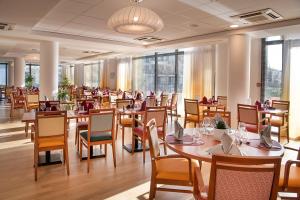 新城勒鲁瓦多米蒂斯莱沙布勒多洛公寓式酒店的餐厅设有木桌、椅子和窗户。