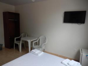 萨尔瓦多Suite Vista Mar的一间带床和两把椅子的房间以及一台电视