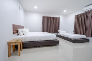 尖竹汶Myrrh Hotel Chanthaburi的一间卧室配有两张床和一张桌子