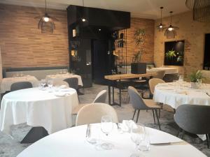 朗贡Logis Hôtel - Restaurant Maison Claude Darroze的一间设有白色桌椅的用餐室