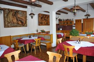 洛伊塔施和平山生活旅馆的餐厅设有桌椅,墙上挂有绘画作品