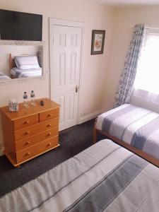 基尔肯尼Billycan Guest Rooms的一间卧室设有两张床、一个梳妆台和窗户。