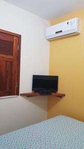 巴拉格兰德Pousada Barra Sol的一间卧室配有一张床,墙上配有电视