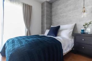 大阪Villa Penthouse Tenma的卧室配有蓝色和白色的床和窗户。