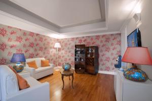 陶尔米纳卡帕莱纳酒店的客厅配有白色家具和红色花卉壁纸