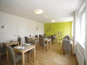 圣卡尼兹Pension Christiane的一间带桌椅和绿色墙壁的餐厅
