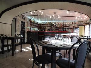 贝莱姆Logis Hôtel Restaurant L'Escale的一间带桌椅的餐厅和一间酒吧