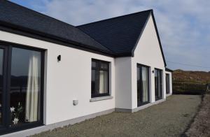 塔伯特Dunarain Bed & Breakfast的白色的房子,有黑色的屋顶和窗户