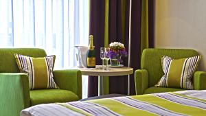 博帕德兰德卡斯福里特尔酒店的两把绿色椅子和一张桌子,桌子上摆放着酒杯和鲜花