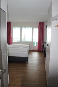 达沃斯Bernina Bed and Breakfast的一间卧室配有床和一个带粉红色窗帘的窗户。