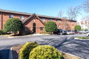 夏洛特Extended Stay America Select Suites - Charlotte - Tyvola Rd - Executive Park的停车场内有汽车停放的砖砌建筑