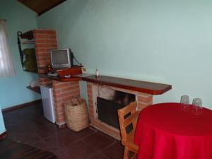 贡萨尔维斯Pousada Recanto da Vitória的客厅设有壁炉、桌子和电视