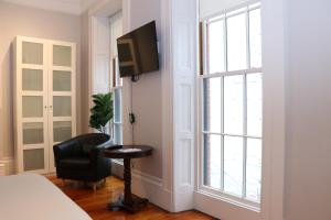 波士顿Charming & Stylish Studio on Beacon Hill #8的一间卧室配有一张床和一把椅子,墙上配有电视
