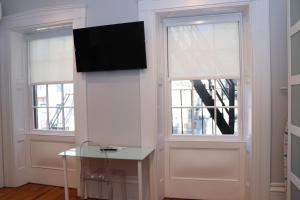 波士顿Downtown Beacon Hill, Convenient, Comfy Studio #10的客房设有2扇窗户,墙上配有电视。
