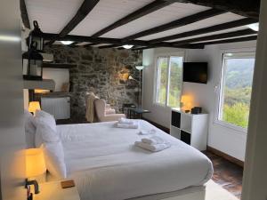 O CarballoCasa Campacinas Casas Vacacional con vistas del rio的卧室配有一张白色的大床和石墙