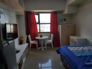 宿务KC Studio 6 at Horizon 101 Cebu的一间卧室配有一张床、一张桌子和一个窗户。