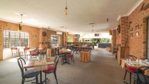 科夫斯港Country 2 Coast Motor Inn Coffs Harbour的一间带桌椅的餐厅以及砖墙