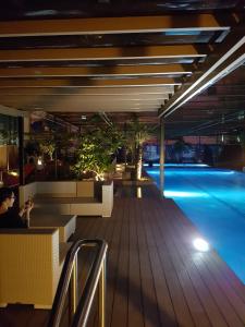 宿务KC Studio 6 at Horizon 101 Cebu的夜间与坐在桌子上的人的游泳池