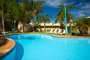 埃克斯茅斯珀索特度假酒店的一个带椅子的游泳池,棕榈树
