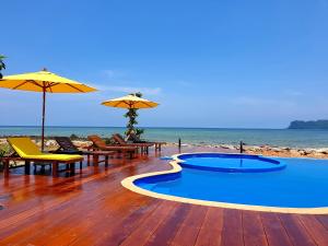 跋麒The Beach Resort & Residence - SHA Plus的海滩上带游泳池、椅子和遮阳伞的甲板