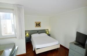 巴里左狄雅库斯公寓的一间白色卧室,配有床和电视