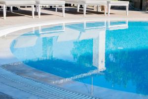 阿菲托斯斯塔莫斯酒店的游泳池设有蓝色的水面和白色的桌子