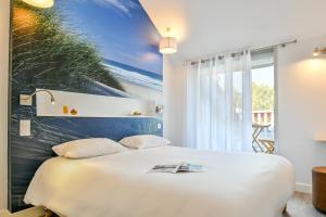 比斯卡罗斯海滩波浪之家酒店的卧室配有一张白色床,墙上挂有绘画作品