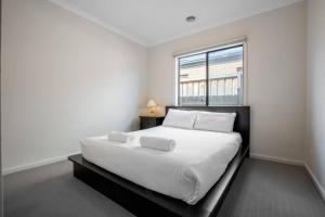 库克角Holiday Rose的白色卧室设有一张大床和窗户