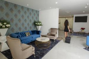 法菲Hotel Fafense的站在客厅的蓝色沙发上的女人