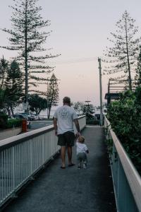 黄金海岸伯利棕榈假日公寓酒店的和孩子一起在桥上行走的男人