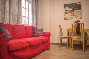 马拉加Apartamento Padilla Playa Huelin的客厅里一张红色的沙发,配有桌子