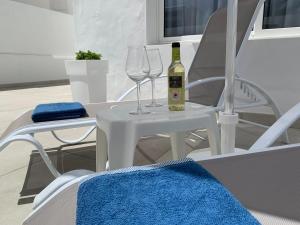 圣巴尔托洛梅Princesa Ico, cerca del mar的一张带两杯酒的白桌和一瓶葡萄酒