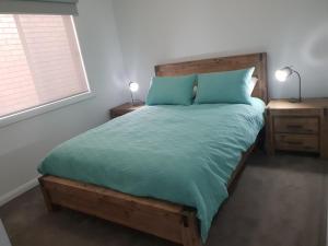 霍舍姆123 Wilson - Arapiles的一间卧室配有一张带绿色棉被的木床