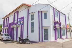 井里汶RedDoorz Plus @ Tuparev Cirebon 2的停在紫色和白色建筑前的摩托车